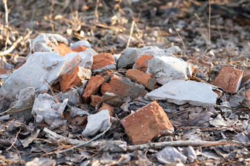 A pile of old broken red bricks with construction debris. Close-up with blurred background.