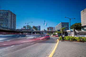 Image of an avenue with moving vehicles in Guatemala City. View of municipal government buildings...