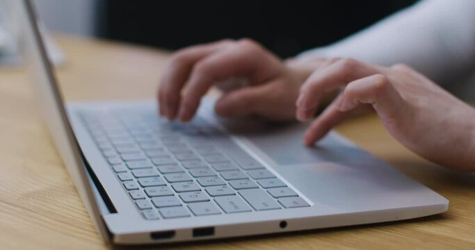 Charming Asian woman spending time on laptop while working online. Studying remotely from home. Positively looking at screen while surfing website. Connected to home network. Typing on keyboard.