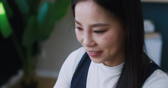 Portrait of Asian worker looking with focus at laptop screen. Having good feelings while working with digital gadget at home or modern office. Woman pressing keys on keyboard while texting.