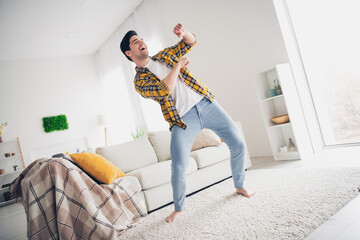 Photo of cool funky man wear checkered shirt staying home dancing indoors house apartment room