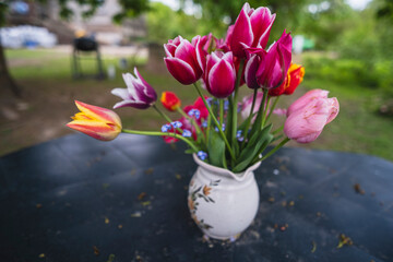 A bouquet of yellow, pink, red tulip flowers on table outdoors in countryside