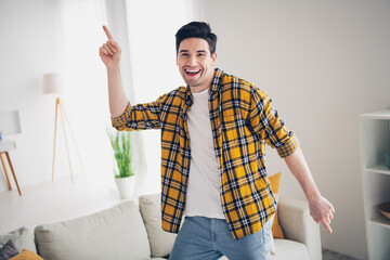 Photo of funky positive man wear checkered shirt dancing staying home pointing finger indoors house...