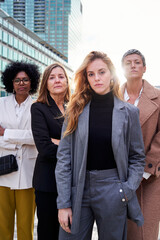 Portrait of a successful group of empowered businesswomen looking at camera with a confident serious face, standing outdoors business district. Vertical copy space photo.