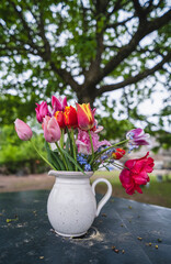 A bouquet of yellow, pink, red tulip flowers on table outdoors in countryside