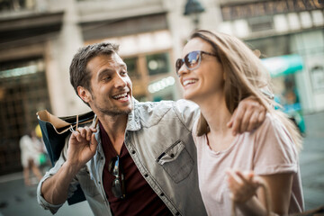 Happy couple shopping and laughing on city street