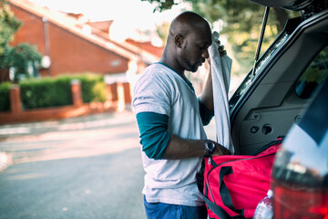 African American man packing sports equipment into car after workout