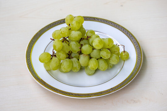 A bunch of green grapes on a white plate. 