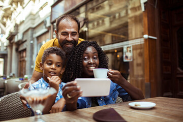 Happy multiracial family taking a selfie at an outdoor cafe