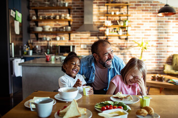Father laughing with children at kitchen table