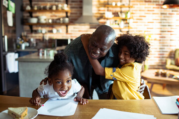 African American grandfather hugging grandchildren while drawing at home