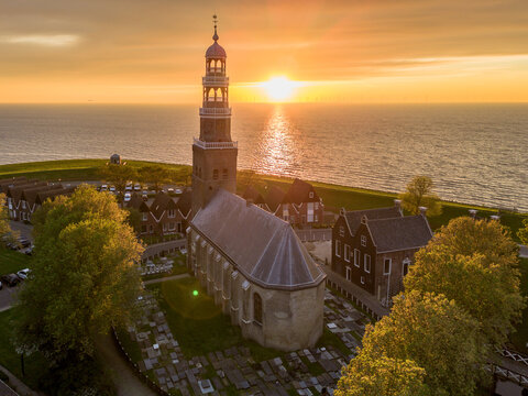 Aerial drone image of historic small city of Hindeloopen, Hylpen with dike, marina, seawall, next to IJsselmeer lake with iconic church and village during spectacular sunset