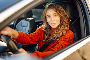 Beautiful Smiling woman driving car, attractive girl sitting in automobile. Young traveler driving. Car travel, lifestyle concept.