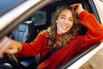 Beautiful Smiling woman driving car, attractive girl sitting in automobile. Young traveler driving. Car travel, lifestyle concept.