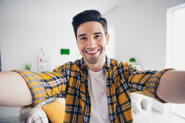 Photo of funky good mood man wear checkered shirt staying home tacking selfie indoors house...