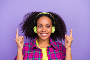 Photo portrait of lovely young lady headphones point up empty space dressed stylish plaid garment isolated on purple color background