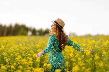 Beautiful woman walks run along yellow field rapeseed. Nature, fashion, summer lifestyle.