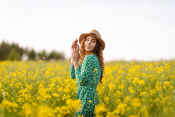 Fototapeta premium Beautiful woman walks run along yellow field rapeseed. Nature, fashion, summer lifestyle.