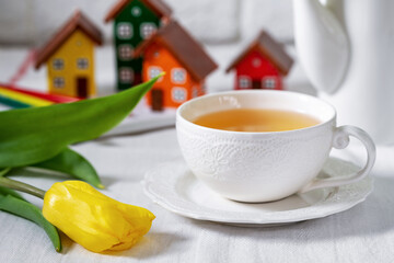 A white cup of tea on the table on a light background