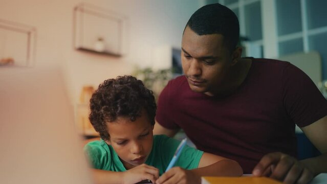 African American dad assists diligent son with homework, providing support