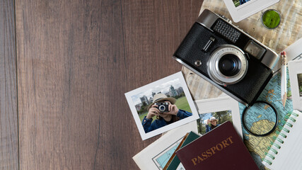 Photographs of woman taking photos, passports, old photo camera, map and notebook on a dark wooden table