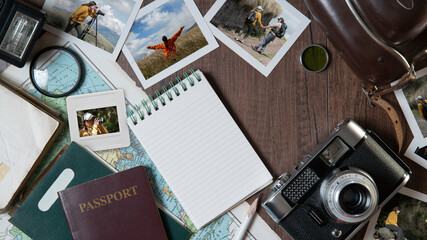 Couple photographs, travel photos, passports, old camera, map and notebook on a dark wooden table