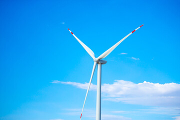 Fleet of power generators in motion. The blades of the wind farm rotate against the sky. The...