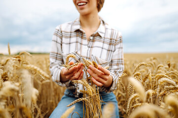 Wheat quality check. Woman Farmer with ears of wheat in a wheat field. Harvesting. Agribusiness. Gardening concept.