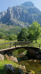 Fototapeta premium A bridge spans a river in a lush green valley. The valley is surrounded by mountains, and the bridge is the only way to cross the river. The scene is peaceful and serene
