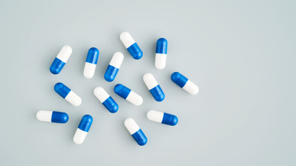 A lot of white and blue pills on a blue background.