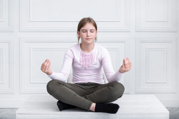 Little schoolgirl sitting on the desk and meditating because of tired of boring education