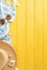 Seaside allure depicted: Top-view vertical composition showcasing sunhat, sunglasses, island trinkets, blanket, shells, starfish on sunny wooden surface, offering area for text or promotional messages
