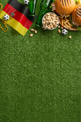 Euro 2024 football atmosphere. Top view vertical shot of Germany flag, championship location. Spread of munchies: hamburgers, nuts, fries. Cool brews on grassy field with space for promotional message