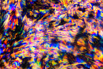 Extreme macro photograph of Meloxicam crystals forming vibrant abstract modern art patterns, when illuminated with polarized light, under a microscope objective with 50x magnification