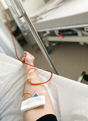 female hand with an IV in the clinic ward. Treatment of anemia in adults. Medical procedure in a hospital inpatient setting.