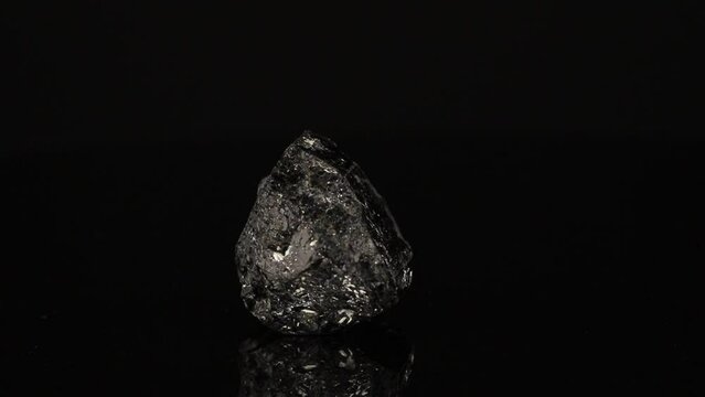 Polished mineral stone Schorl rotates in a circle on a black background