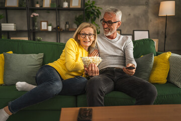Mature senior couple husband and wife watch movie and eat popcorn