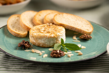 Baked camembert cheese with baguette bread grilled toasts and leaves.