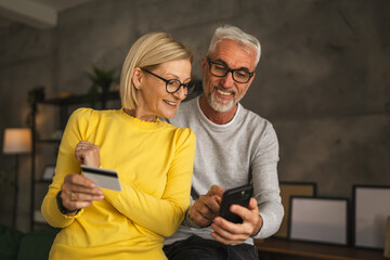 Mature caucasian couple husband and wife shopping online sit at home