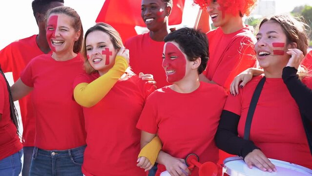 Multiethnic football supporter fans watching soccer match outside of stadium - Diverse people with red t-shirts having excited fun on sport world championship event
