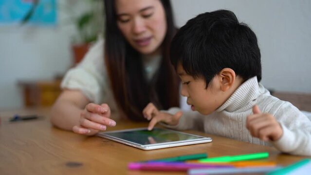 Asian mother and male child using digital tablet indoor - Daycare, technology and education concept