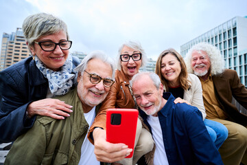 Group happy senior people using mobile phone together outdoor. Elderly friends and smiling...