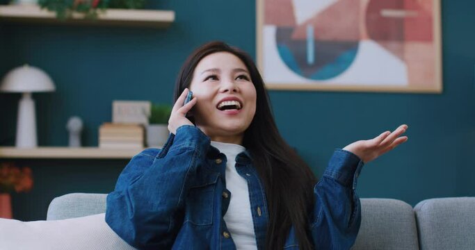 Beautiful Chinese woman talking on smartphone with her friend or boyfriend. Young girl surprised by question during phone conversation. Enjoying good news or invitation. Technology concept.