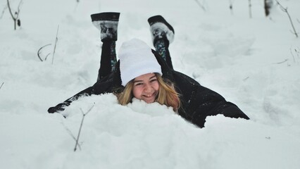 A girl falls on the snow in winter in the forest.