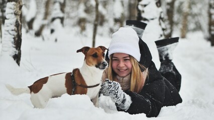 A girl playing with her Jack Russell Terrier dog in the snow.