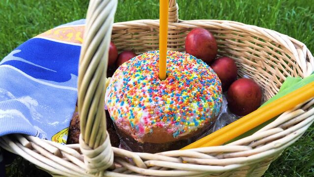 Zoom out of Easter cake, eggs and candles in basket on the green meadow