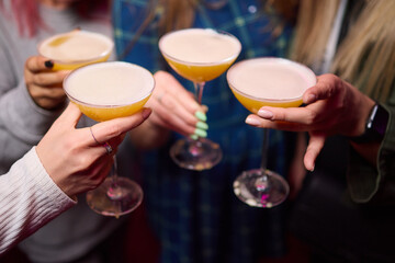 A woman holds a cocktail in her hand, with her fingers wrapped around the glass