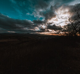 Dramatic sunset over the countryside in winter with dark clouds.