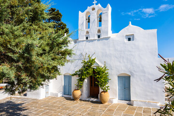 Typical Greek white church with flower pots in Artemonas village against blue sunny sky, Sifnos...