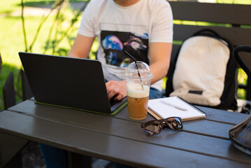 A man works behind a laptop in a summer cafe.